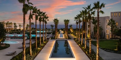 Resort contemporáneo frente al mar con paisajismo, palmeras, piscinas y arquitectura hotelera de lujo, vinculado a selección de talento especializado en arquitectura.